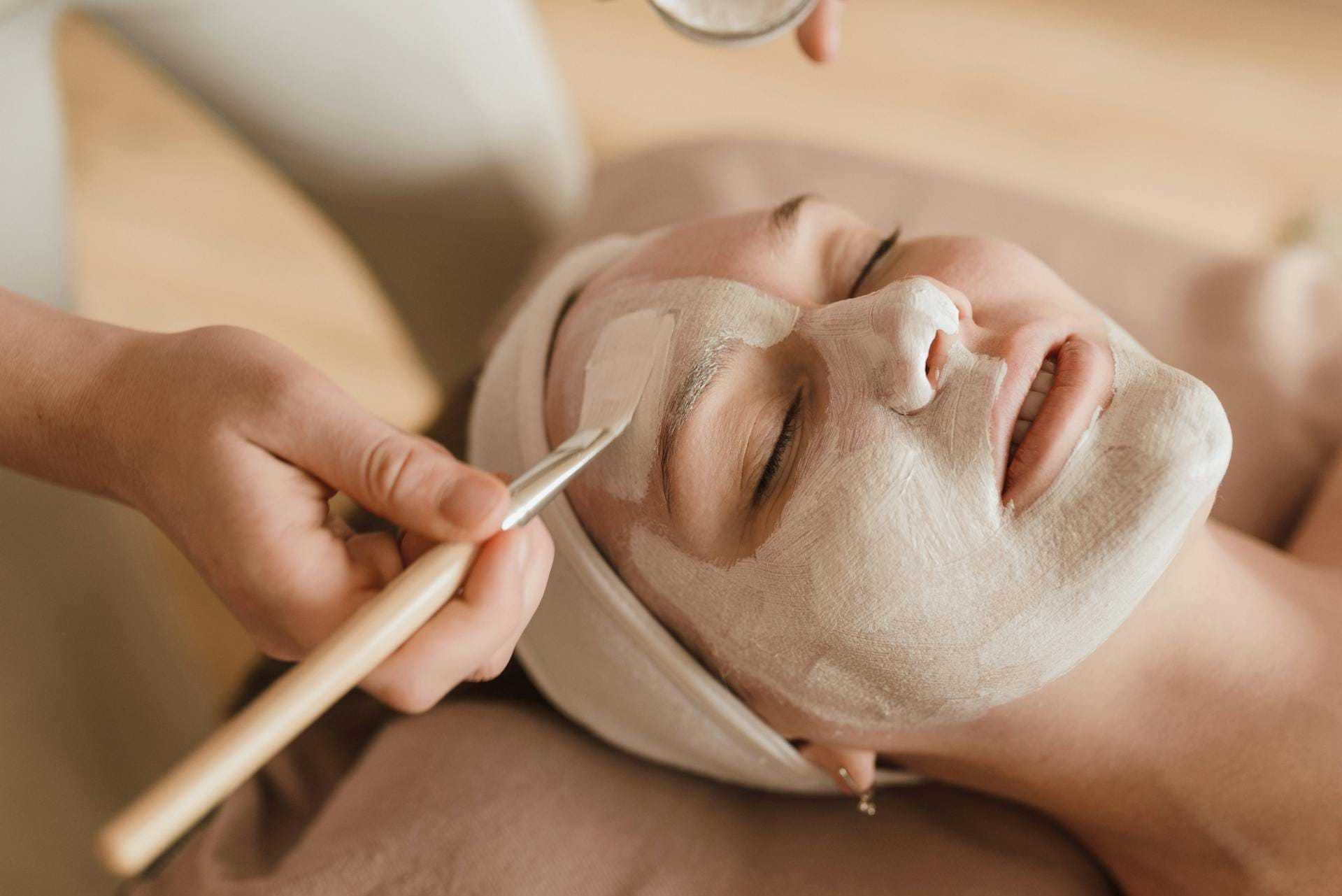 Woman receiving a calming facial treatment with a brush in a spa setting.