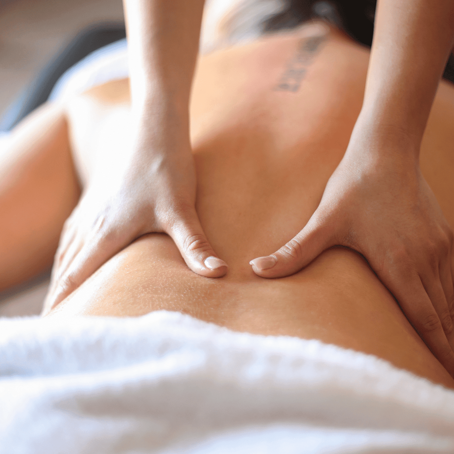 Massage therapist applying pressure on a person's back in a relaxing setting.
