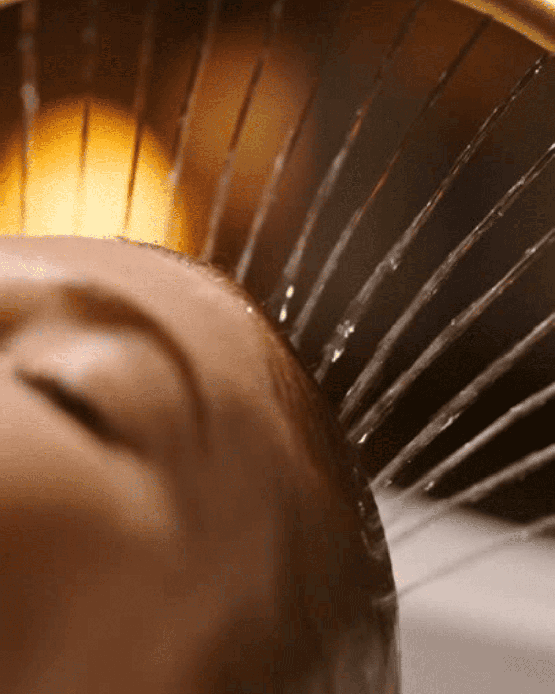 Close-up of a tranquil face in a spa setting with water splashing and gentle lighting.
