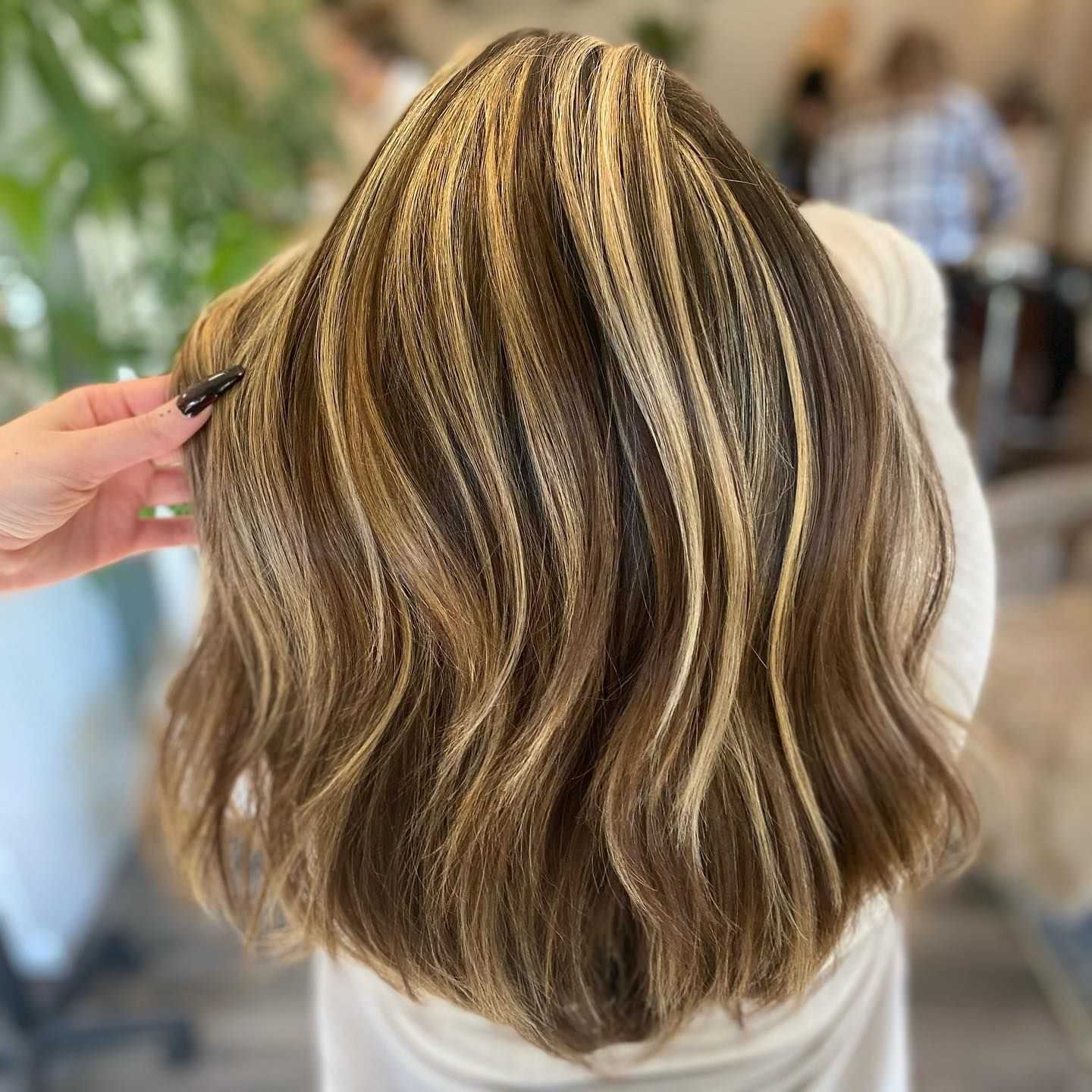 Brown hair with blonde highlights being showcased in a salon.